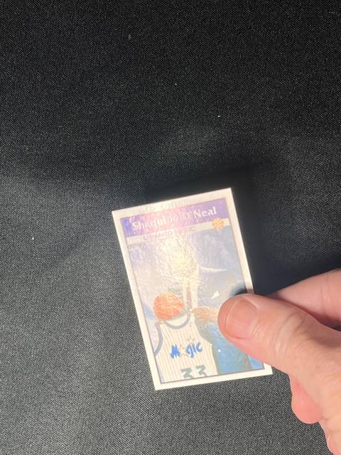 A card held in a hand at an angle with glare washing out the picture